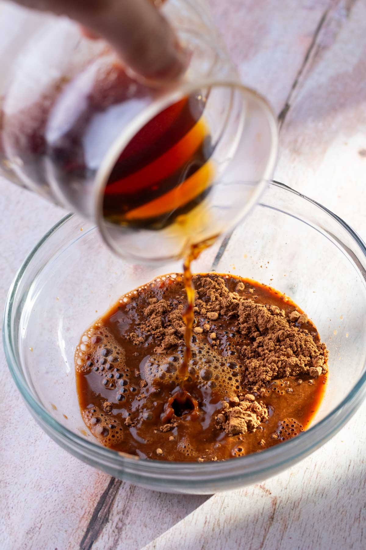 Pouring hot coffee into bowl of cocoa powder to bloom it.