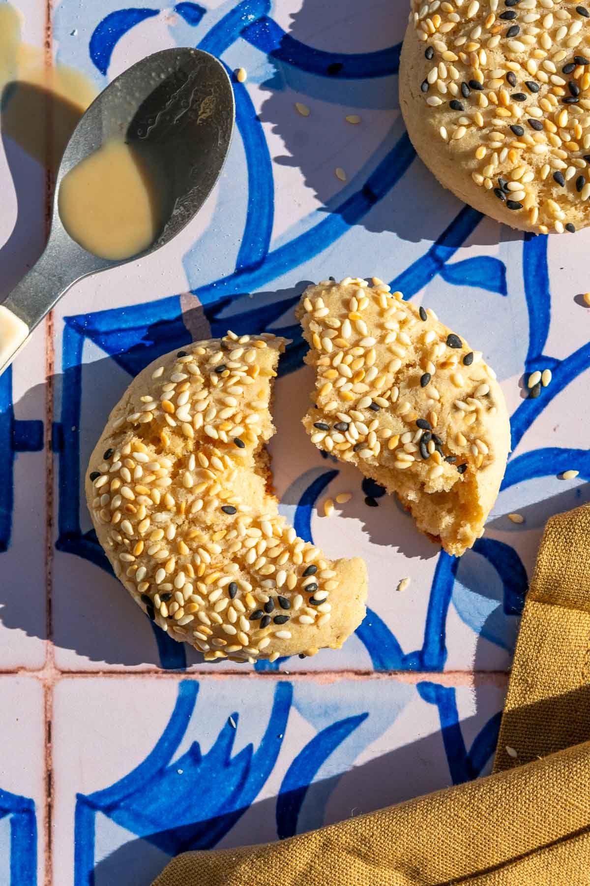 Close up of a sourdough tahini honey cookie broken apart with a spoon with tahini on it.
