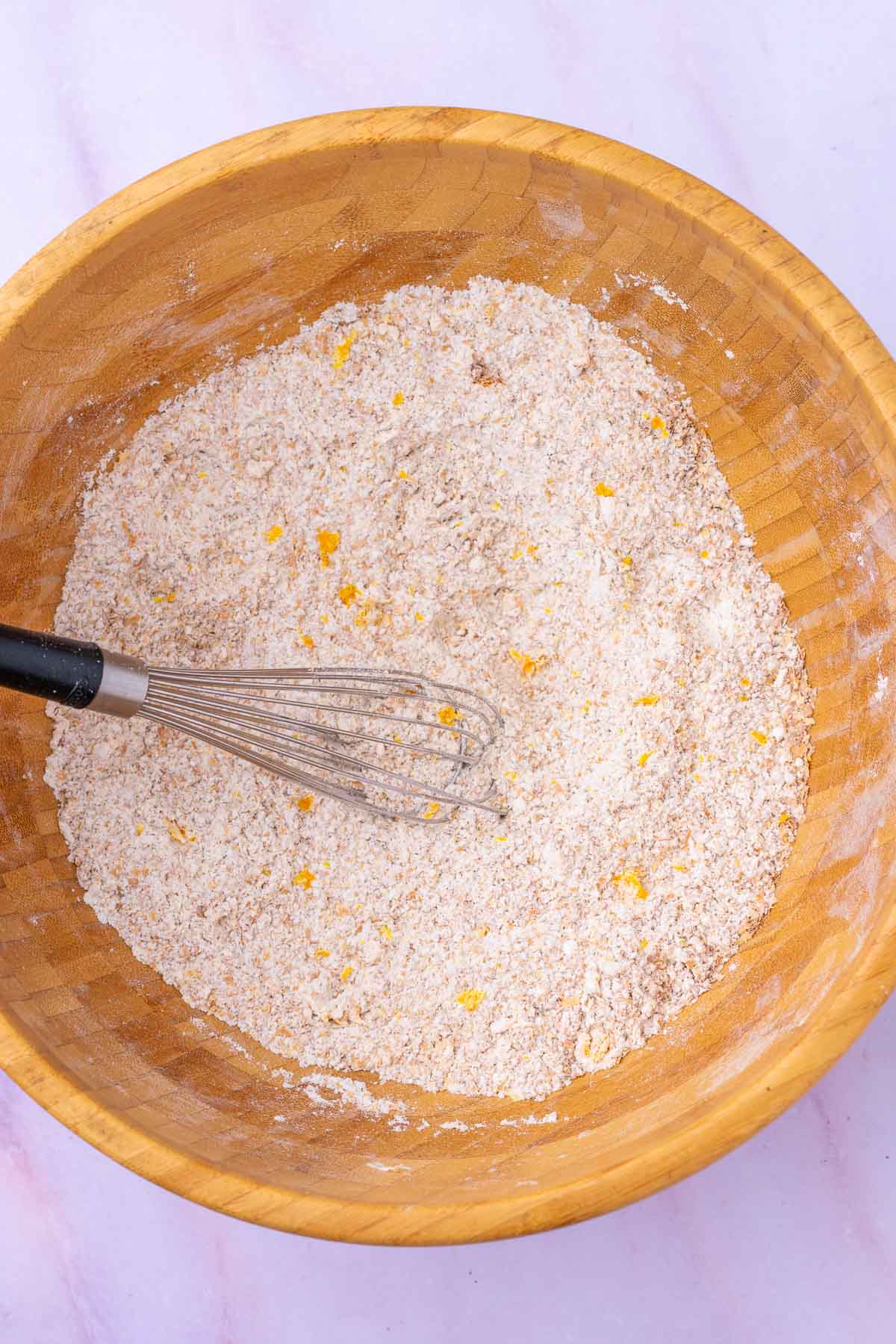 Bowl of mixed dry ingredients for sourdough bran muffins with a whisk.