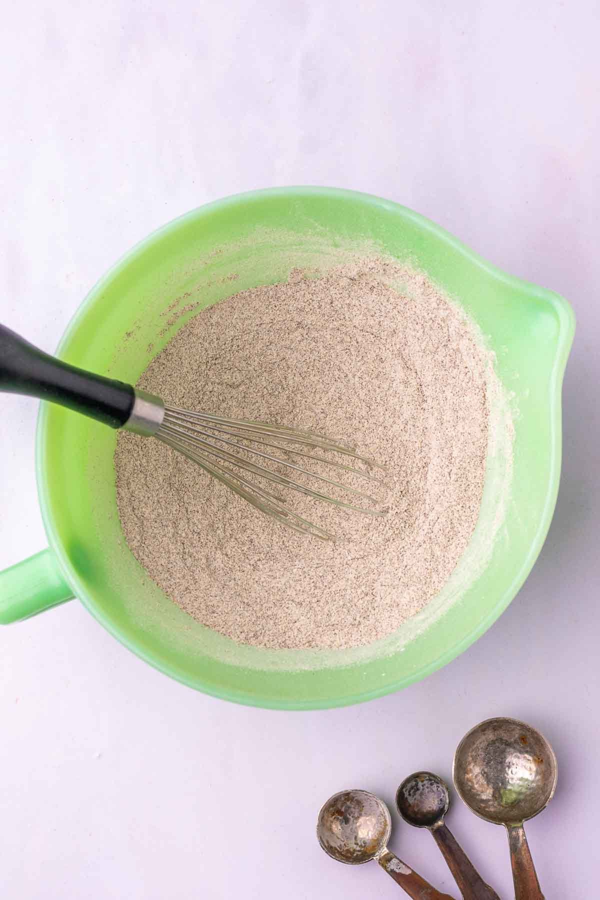 Bowl of dry ingredients for sourdough buckwheat pancakes mixed with a whisk.