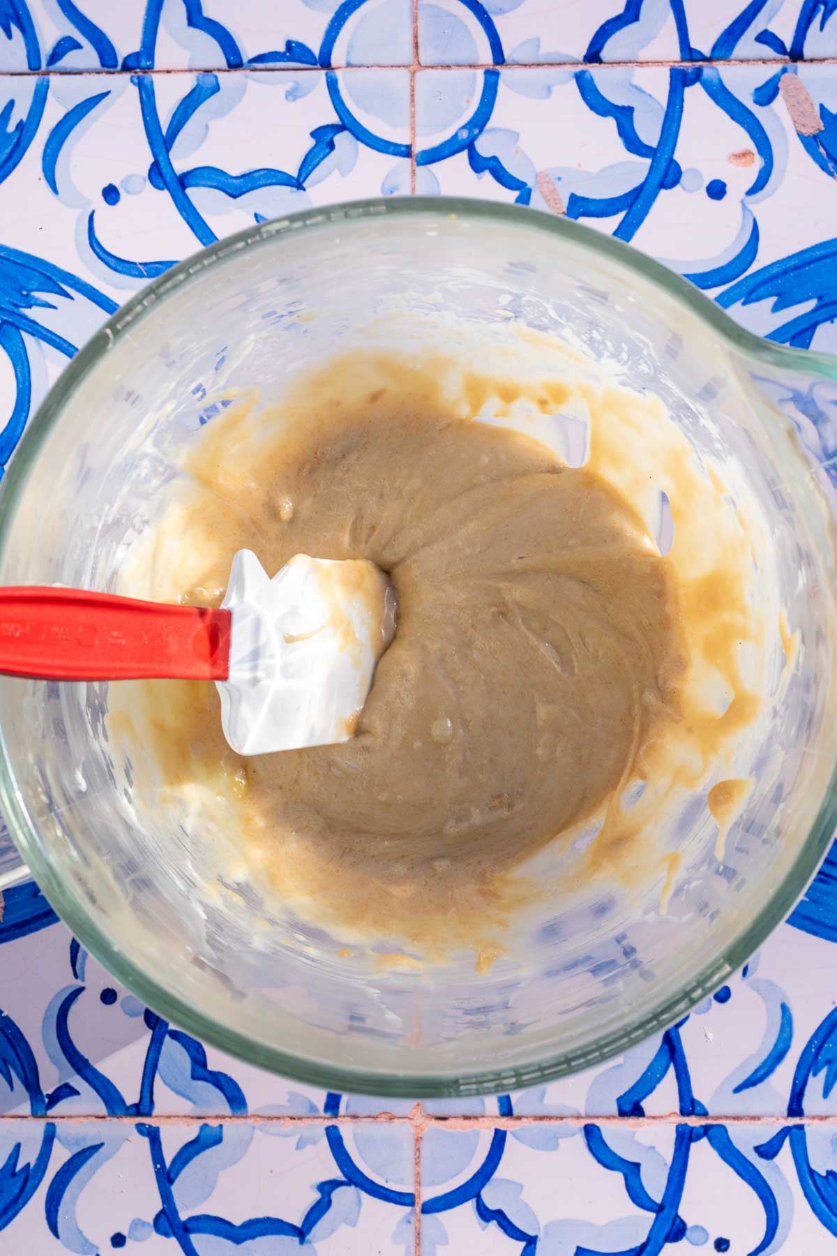 Bowl and spatula of mixed wet ingredients for sourdough tahini honey cookies.