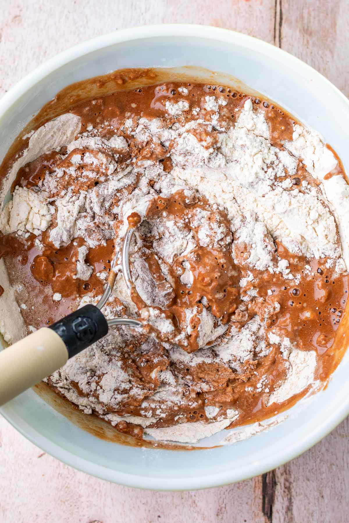Mixing chocolate and coffee into bowl of flour with a dough whisk.