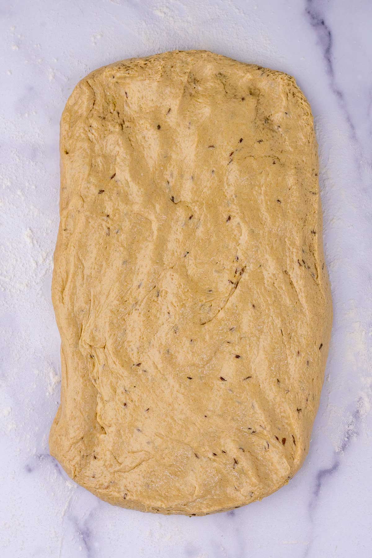 Sourdough rye sandwich bread rolled out into a rectangle.