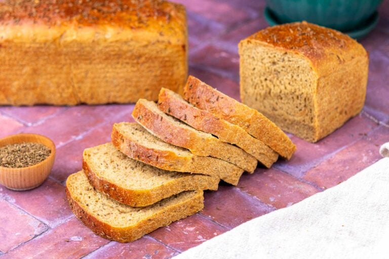 Sliced loaf of soft sourdough rye sandwich bread with caraway seeds.