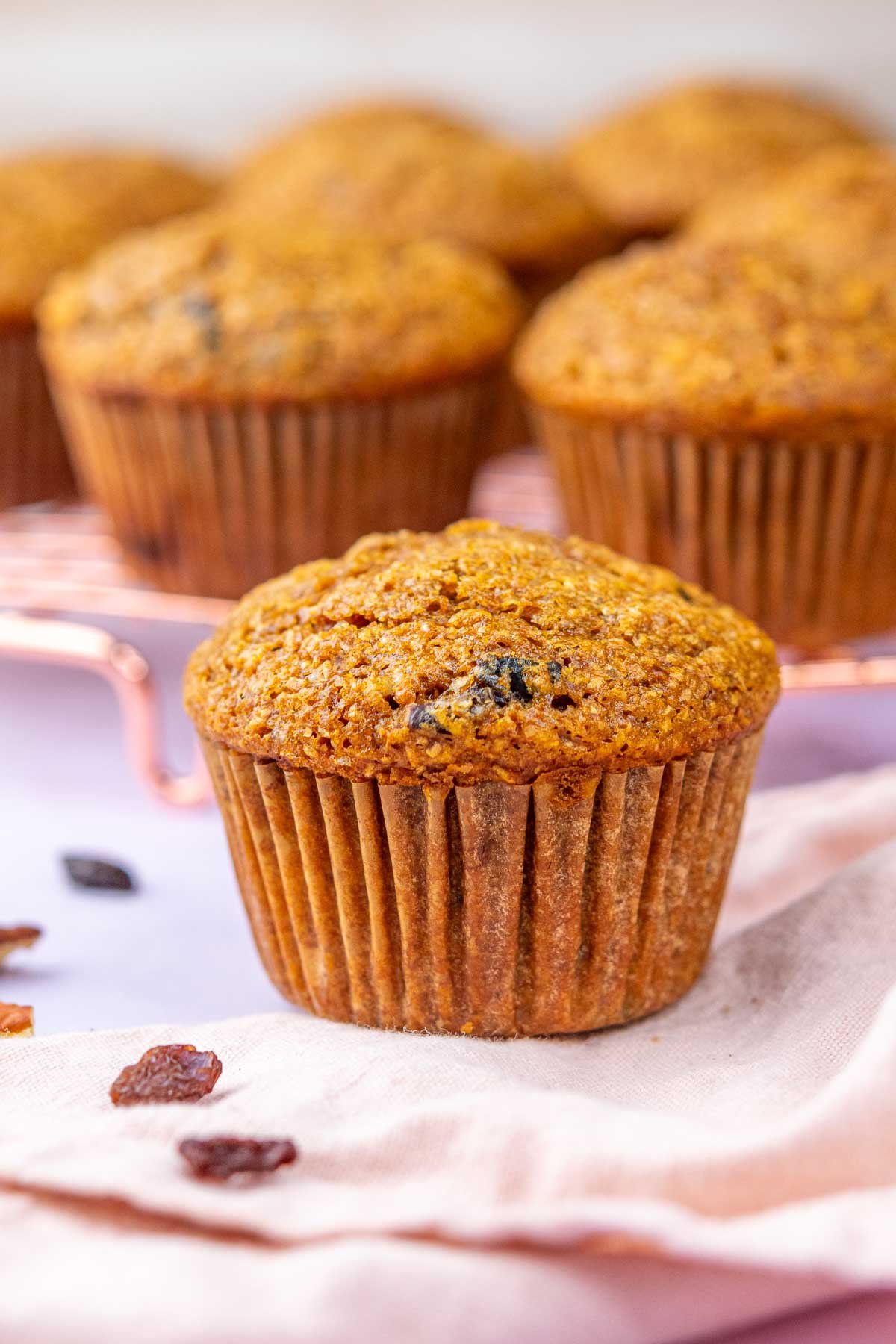 Sourdough bran muffin with pecans and raisins with many more in the background on a wire rack.