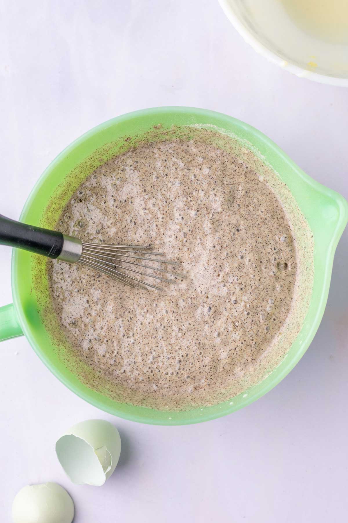 Bowl of mixed sourdough buckwheat pancake batter with a whisk.