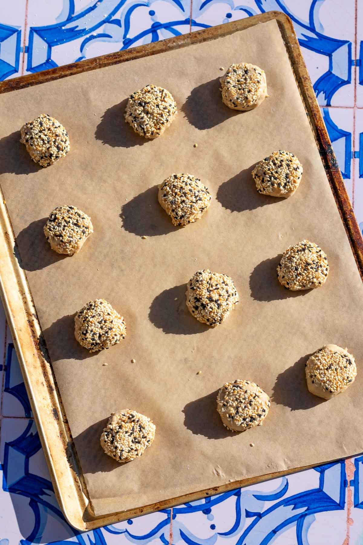 12 unbaked sourdough tahini honey cookies on a parchment lined baking sheet.