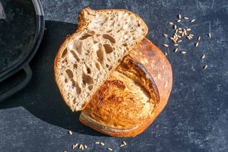 Emmer sourdough bread sliced in half with emmer berries around it.
