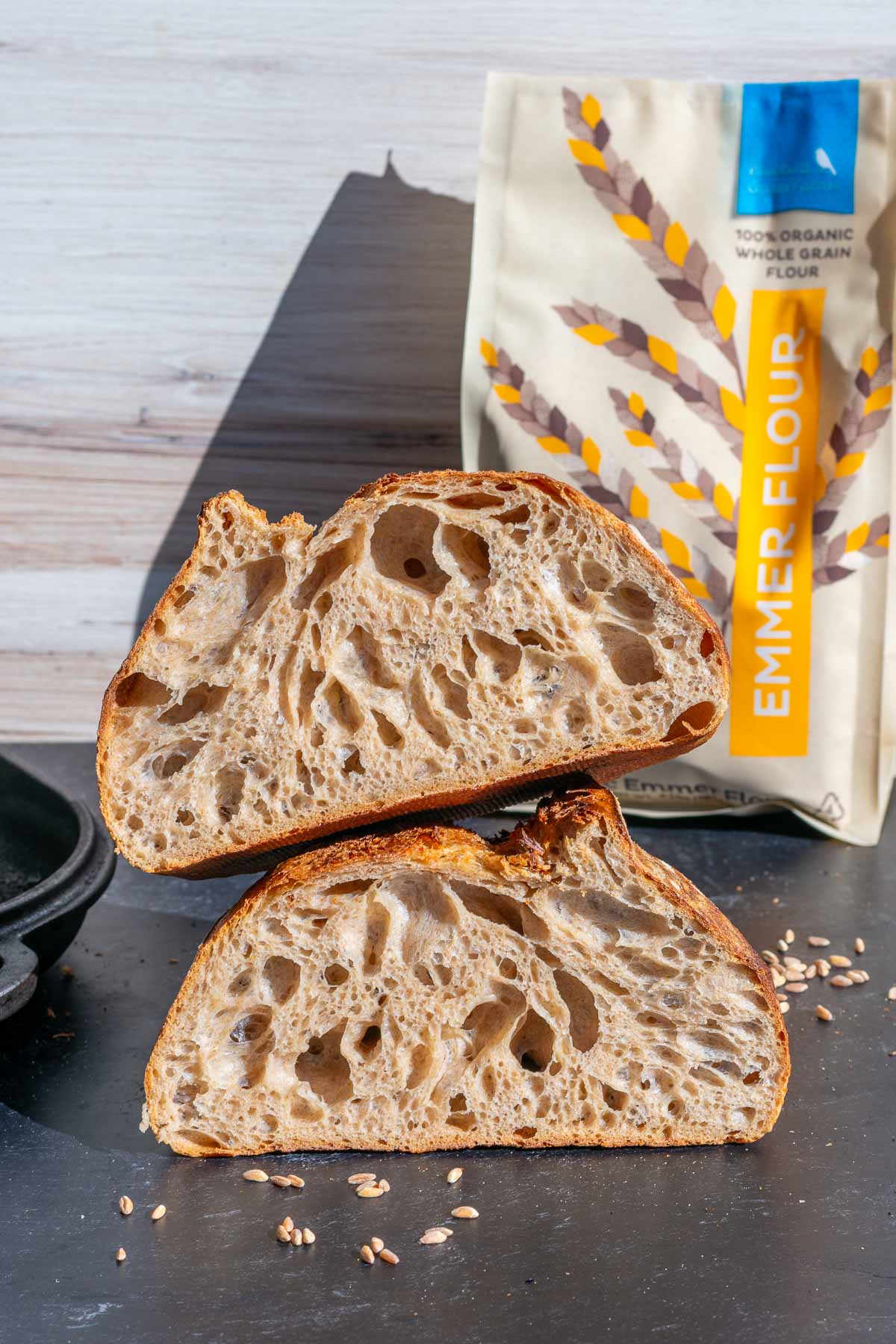 Emmer sourdough bread sliced in half and stacked on top of each other with a bag of emmer flour in the background.