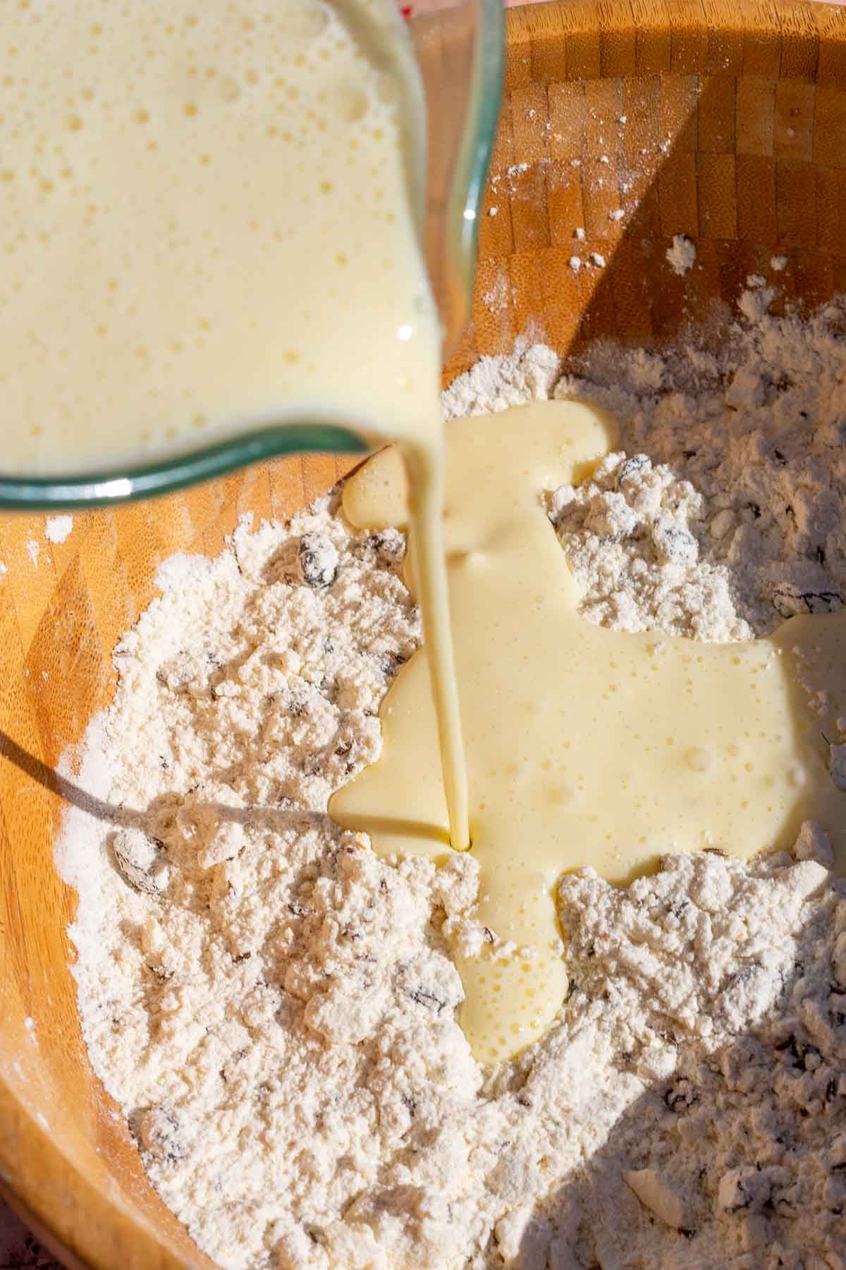 Pouring wet ingredients into bowl of dry ingredients for Sourdough Irish soda bread.