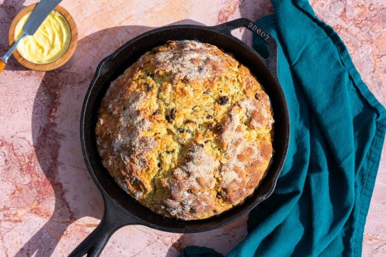 Sourdough Irish soda bread with raisins and caraway seeds baked in a cast-iron skillet with a bowl of butter.