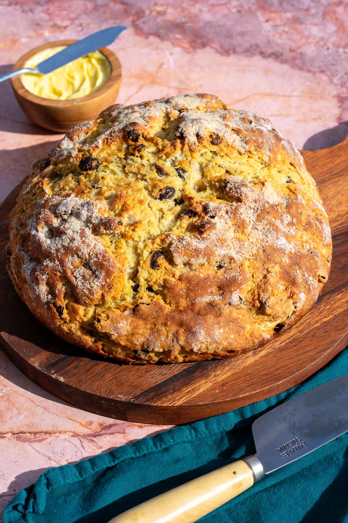 Sourdough Irish Soda Bread on a round cutting board with a knife and a bowl of butter.
