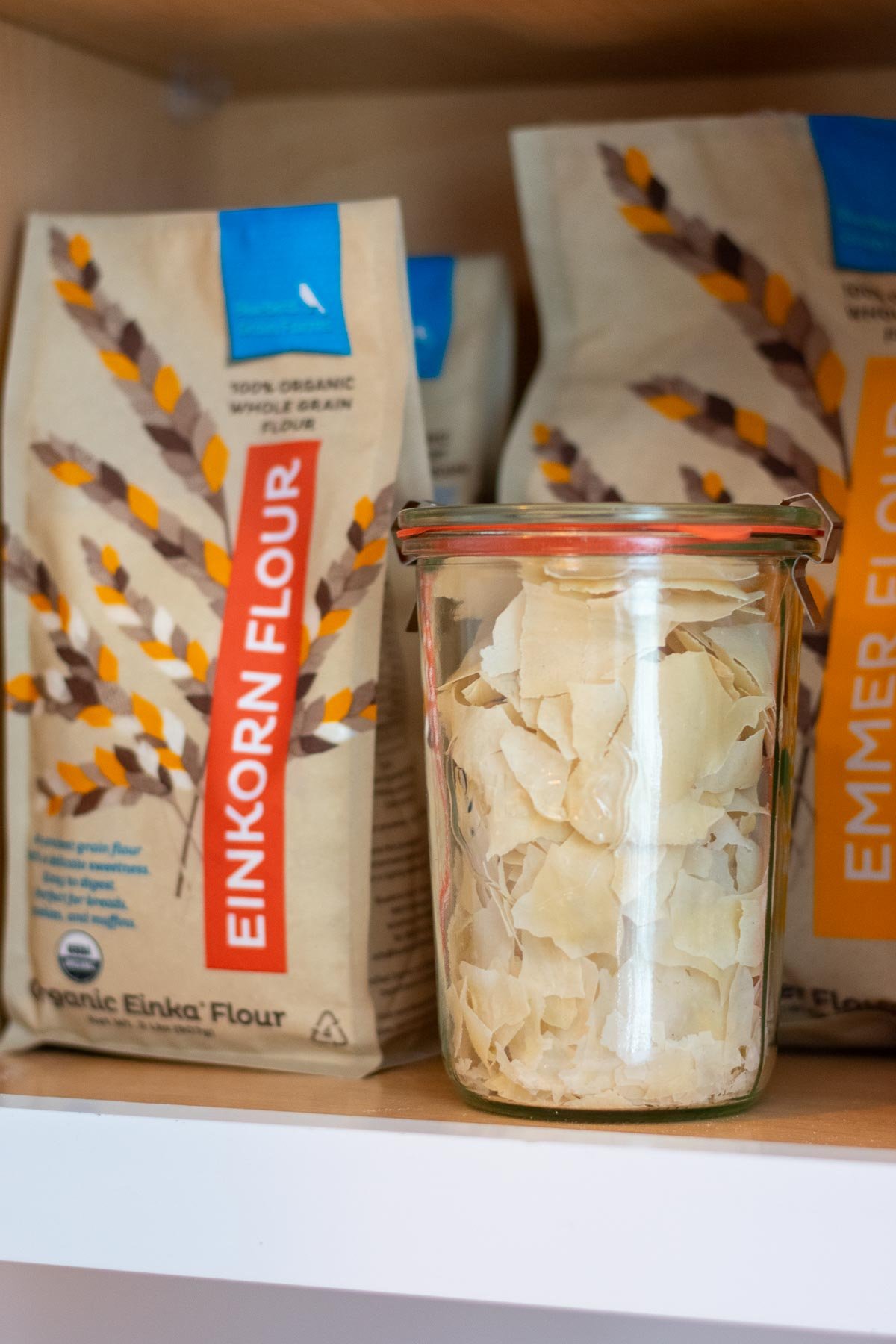 Dried sourdough starter flakes stored in a pantry cabinet with bags of flour.