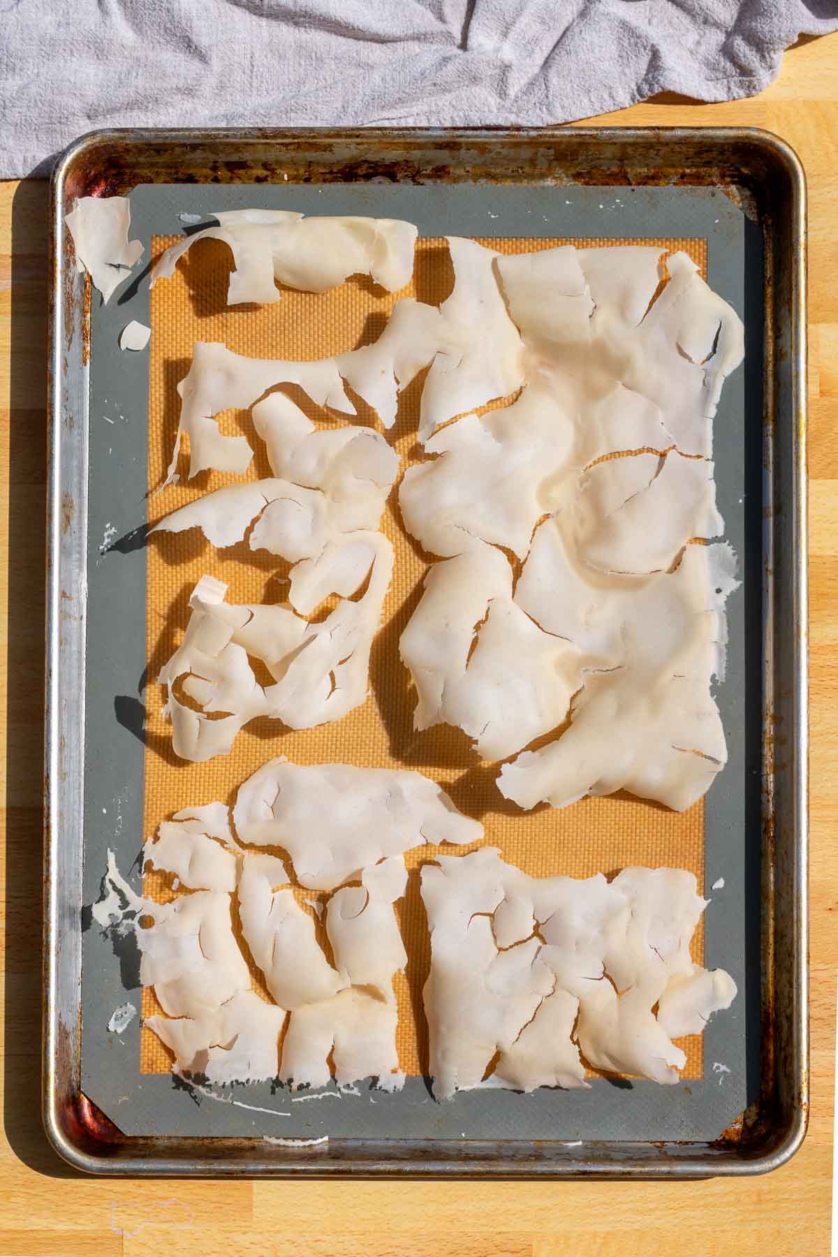Dried sourdough starter on a baking sheet with a silicone baking mat ready to be broken apart into flakes.