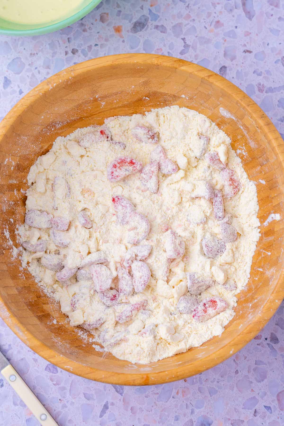 Fresh strawberries added to dry ingredients and butter bowl.