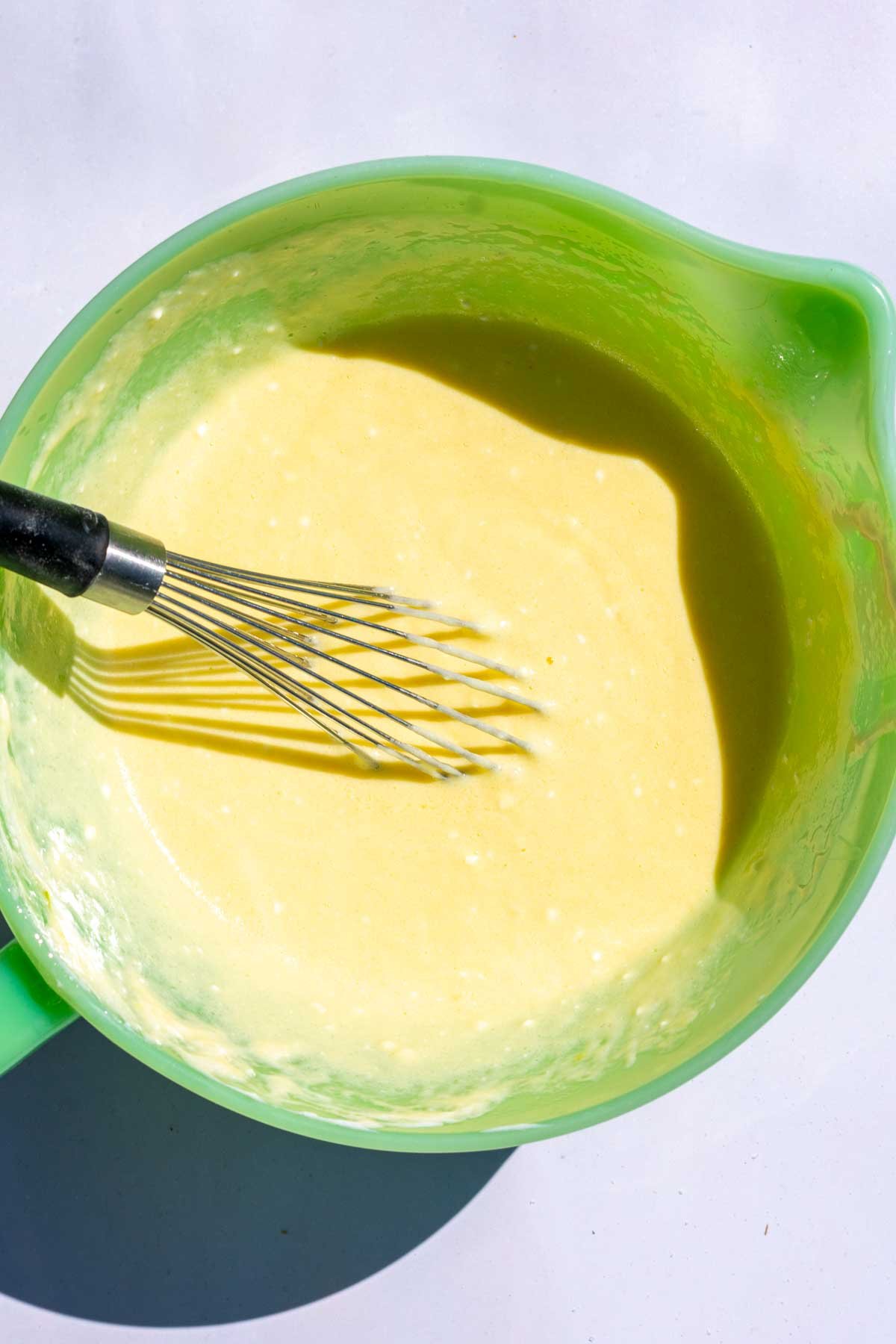 Bowl of mixed wet ingredients with a whisk.