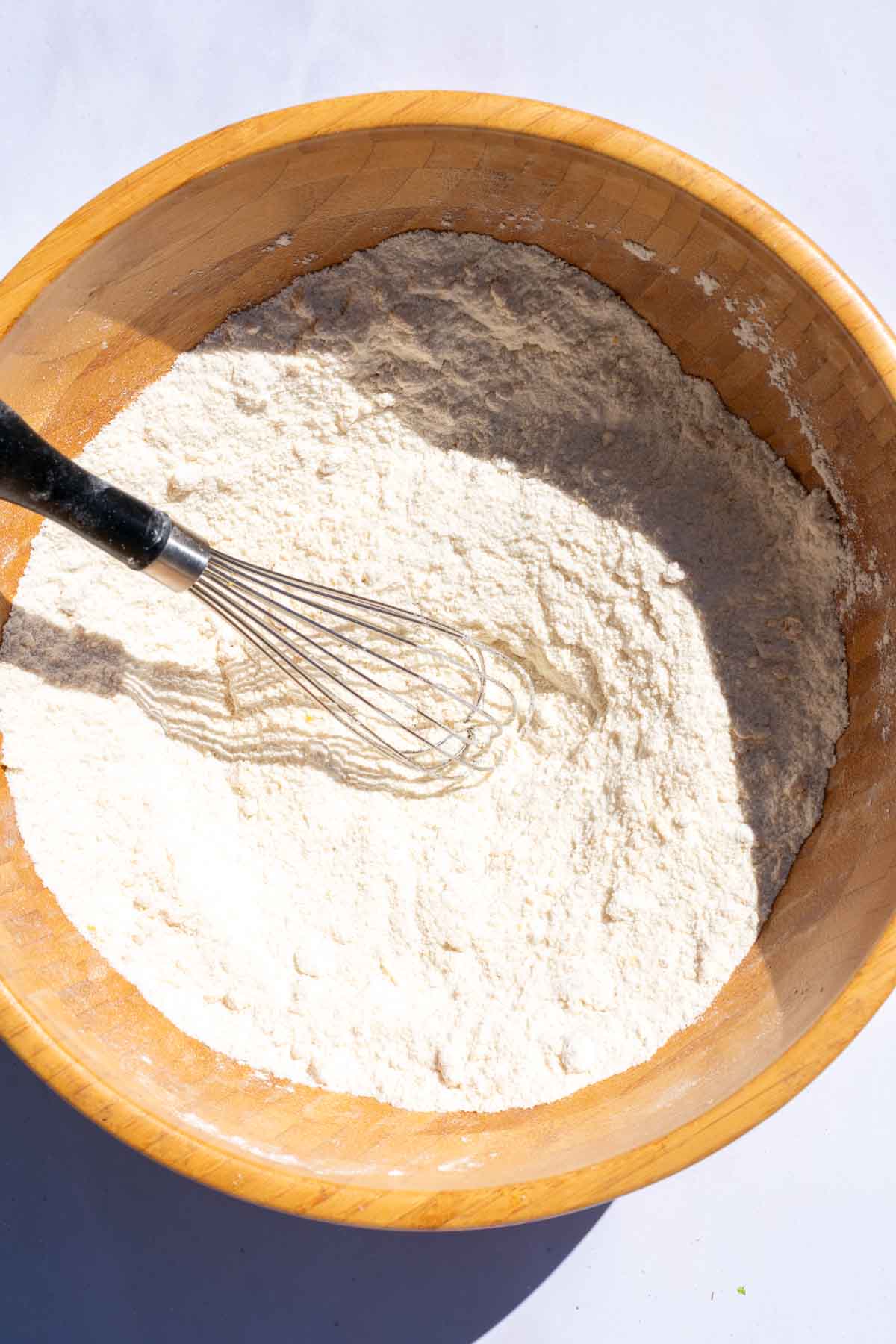 Large mixing bowl of dry ingredients for sourdough blueberry muffins mixed together with a whisk.