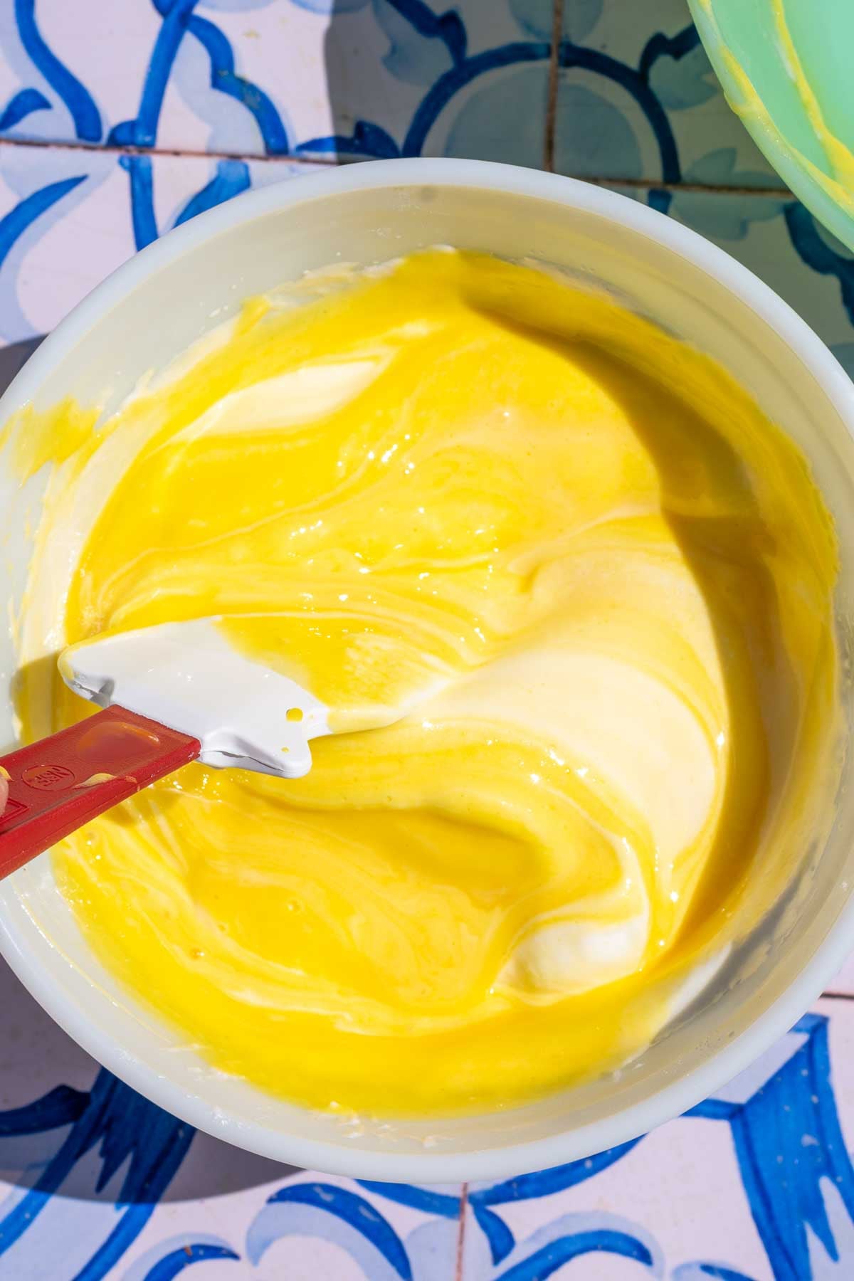 Folding egg yolk mixture into egg whites in a bowl with a spatula.