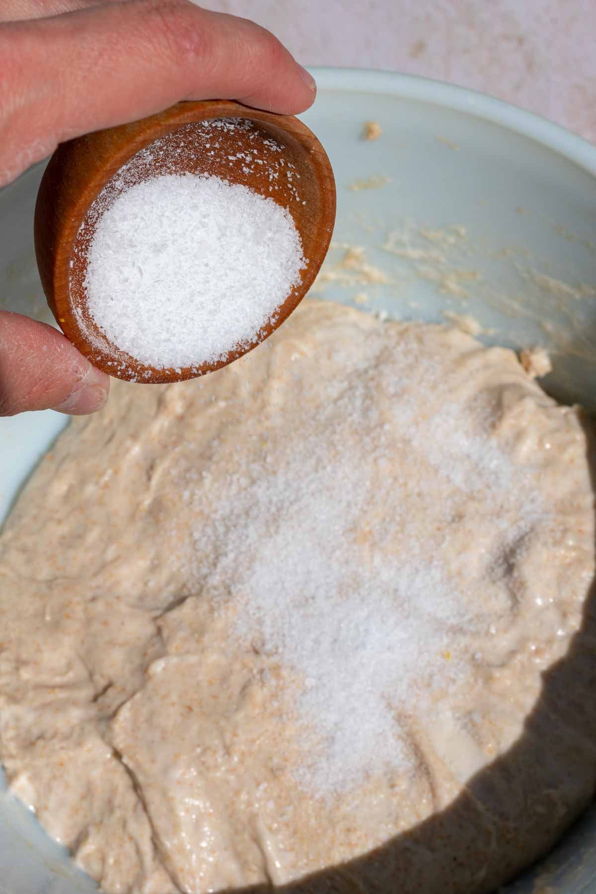 Pouring a small bowl of salt on top of dough.