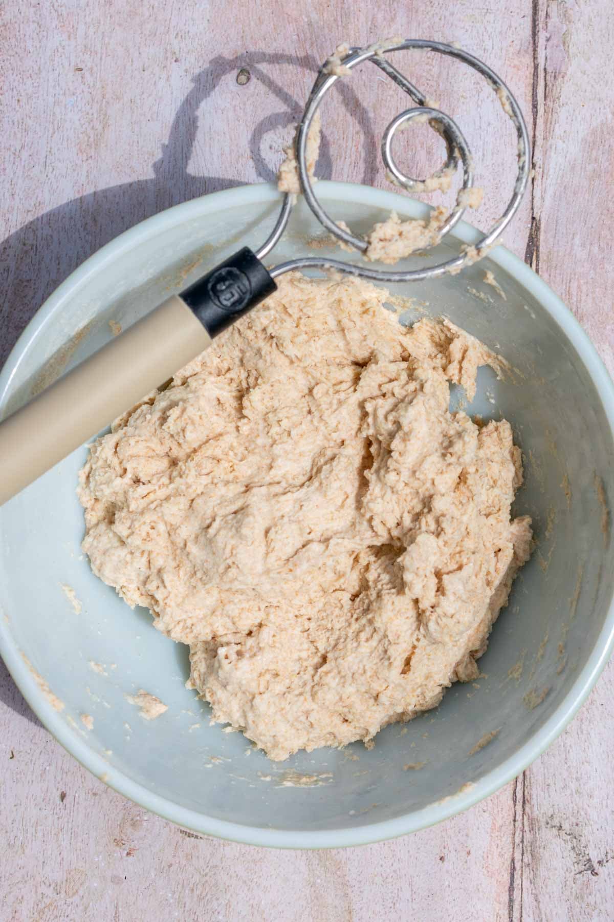 Bowl of flours and water mixed together in autolyse with a dough whisk.