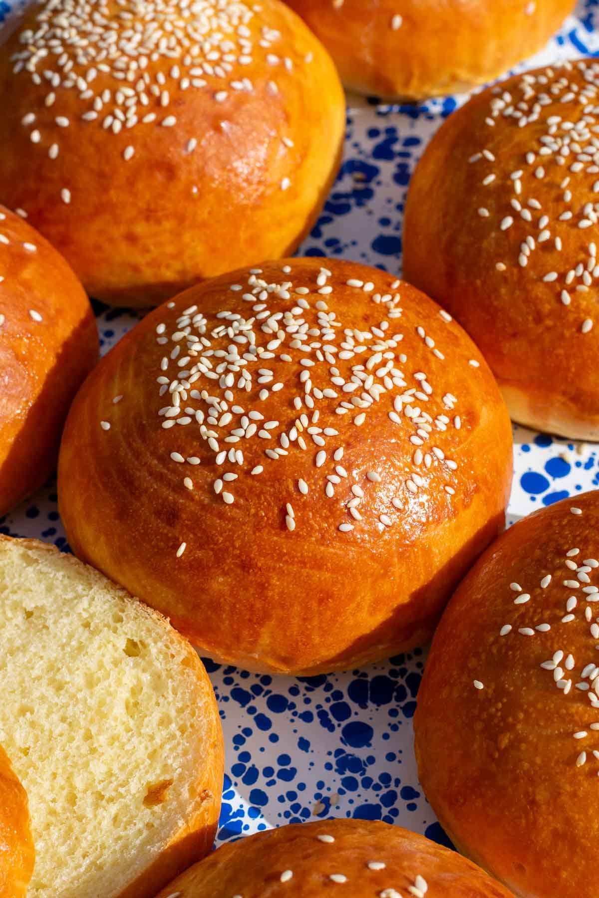 Close up of a baked sourdough brioche hamburger bun topped with sesame seeds.