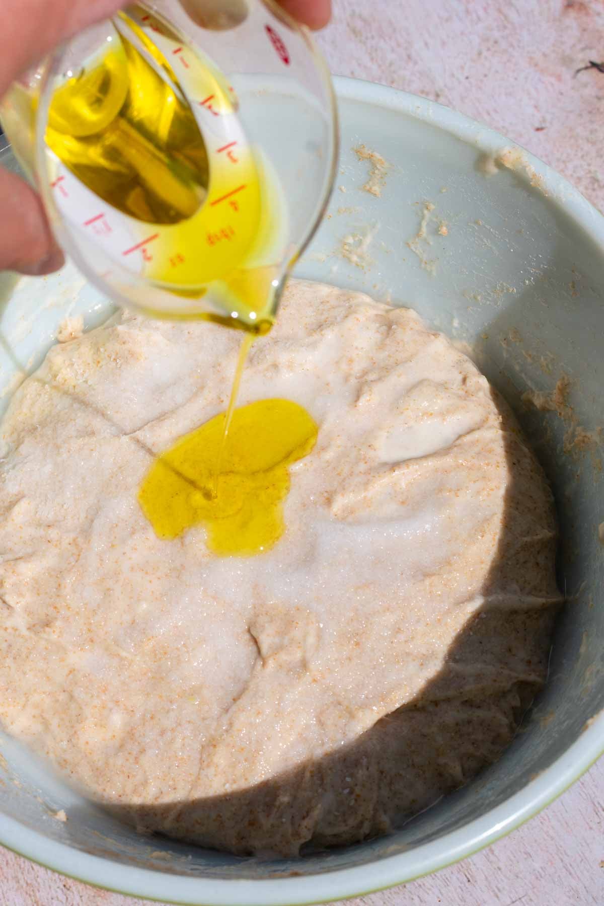 Drizzling olive oil on top of dough.
