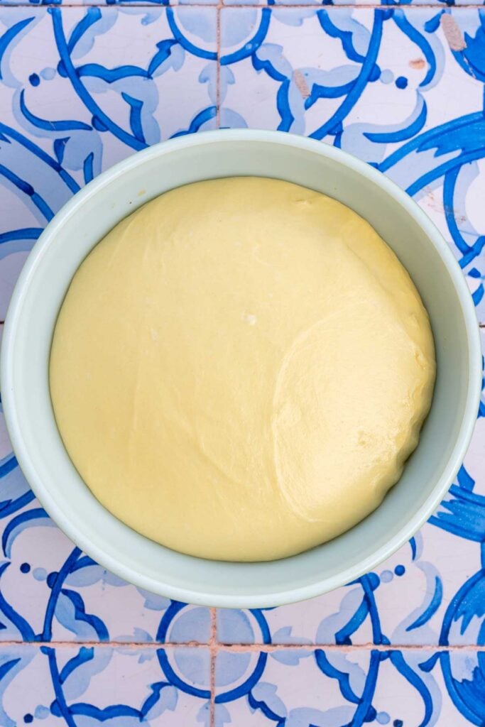 Sourdough brioche hamburger bun dough doubled in size in bowl at the end of bulk fermentation.