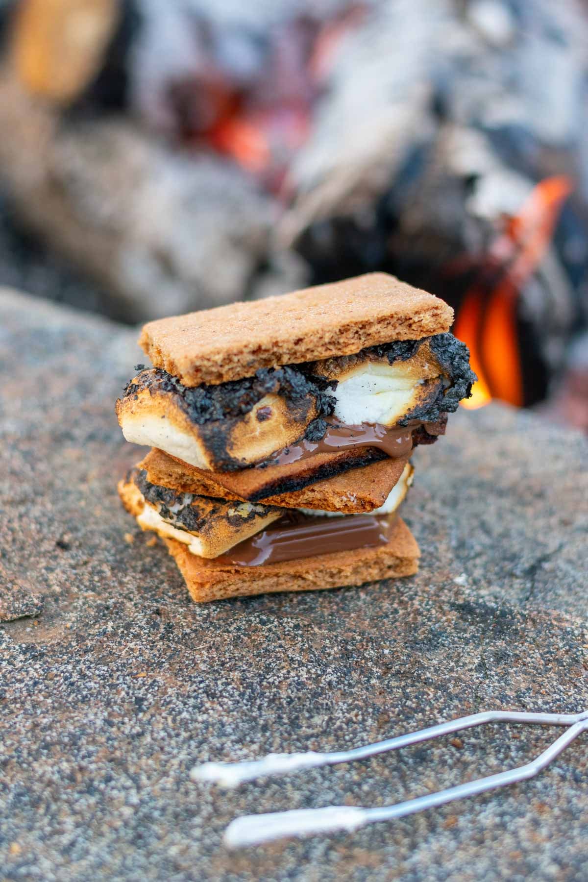 Sourdough graham crackers made into two s'mores in front of a campfire.