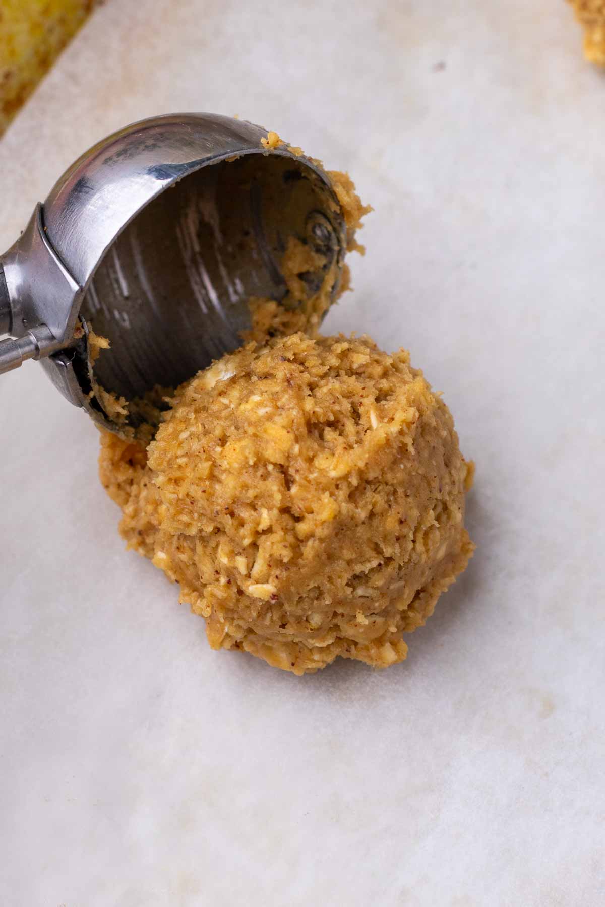 Cookie scoop portioning out a scoop of a sourdough oatmeal cookie.