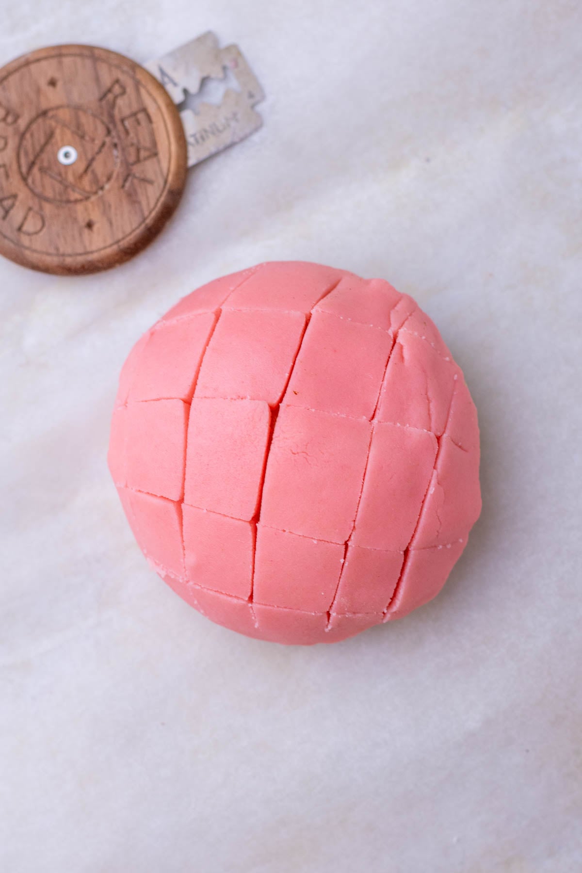 Criss cross pattern scored on sourdough conchas.