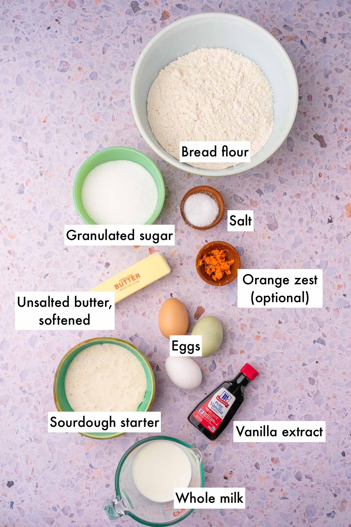 Bowls of ingredients needed for sourdough conchas, including bread flour, sugar, salt, orange zest, butter, eggs, vanilla, sourdough starter, and whole milk.