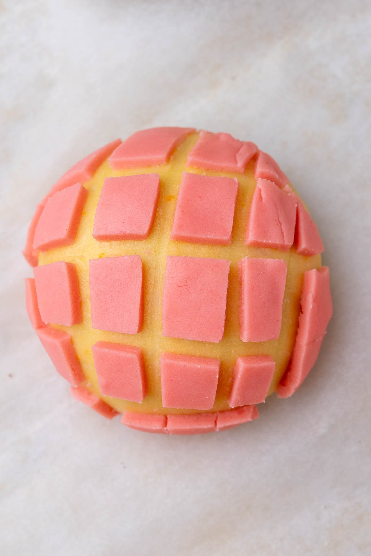 Sourdough concha with pink topping at the end of final proofing.