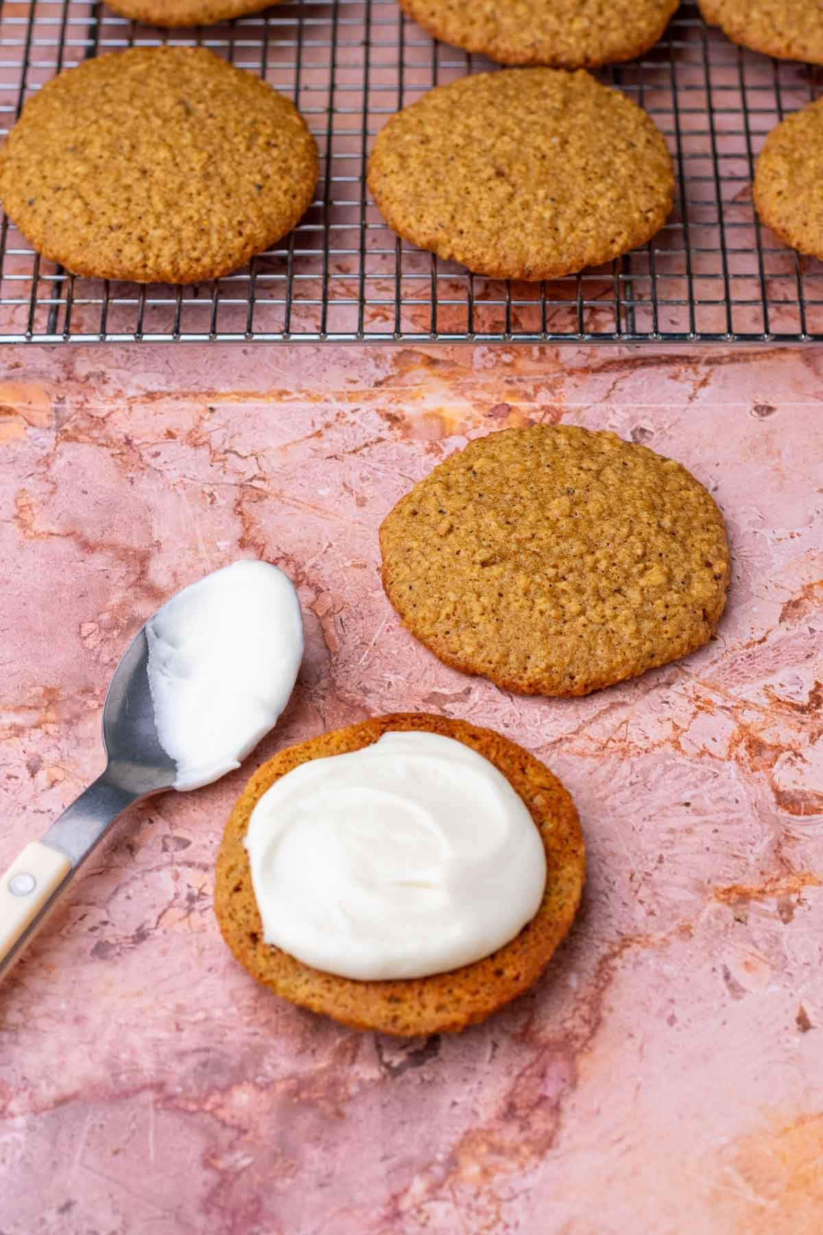 Spooning cream cheese filling on sourdough oatmeal cookies.