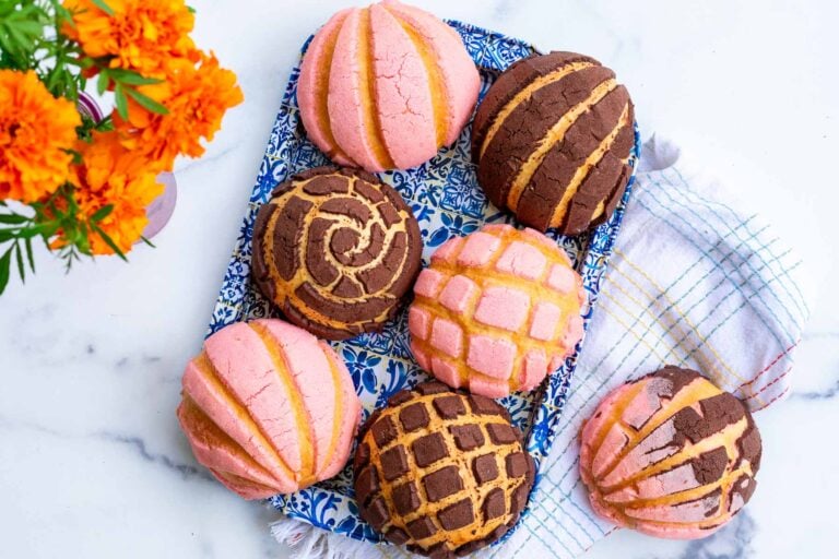 Sourdough conchas with chocolate and strawberry toppings on a platter.
