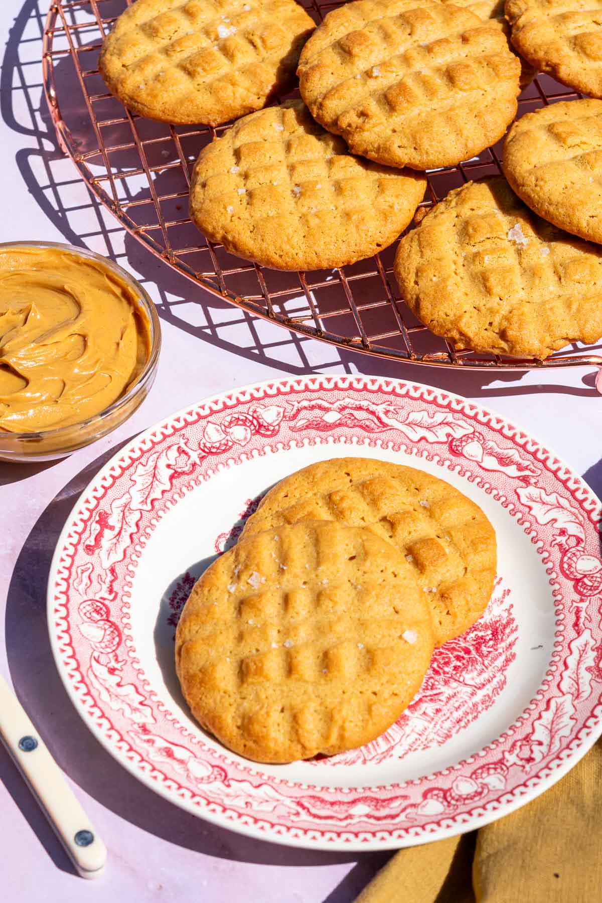 Sourdough peanut butter cookies on a cooling wire rack and on a plate.