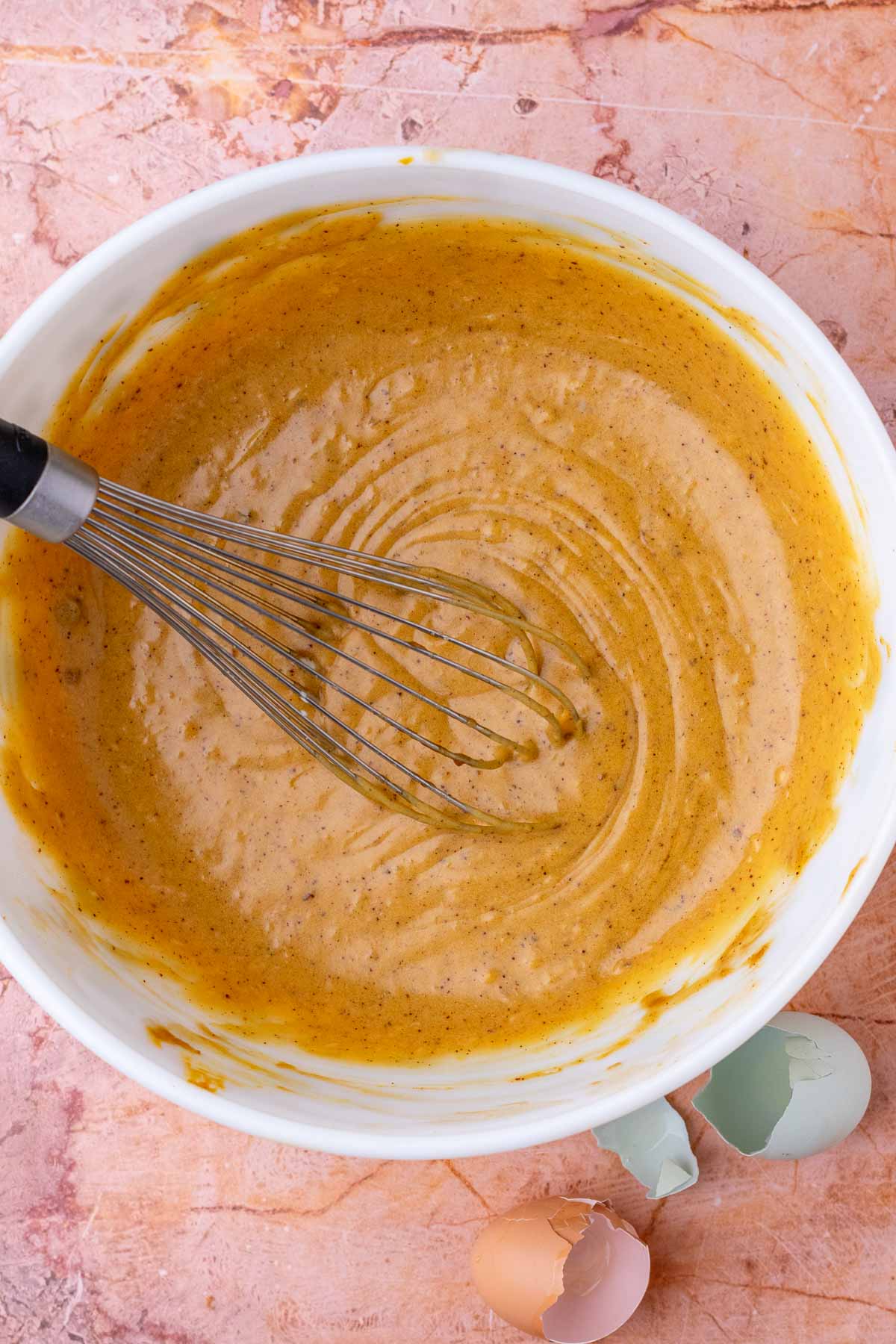 Bowl of mixed wet ingredients for sourdough oatmeal cream pies with a whisk.