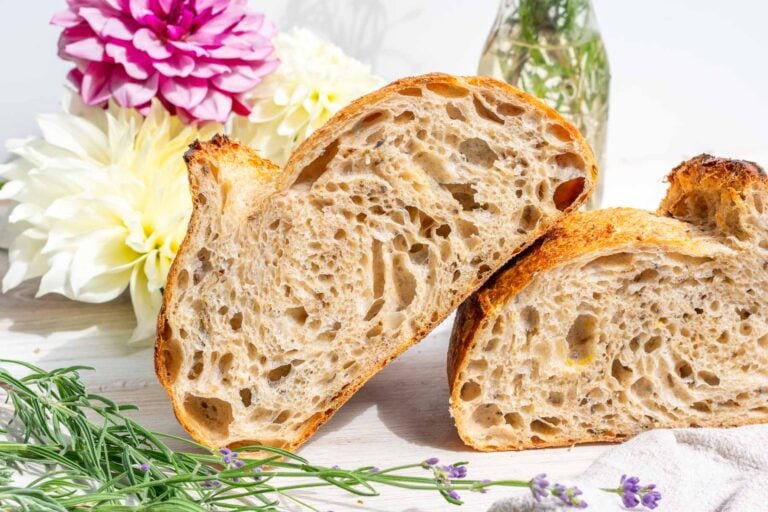 Sliced loaf of lavender vanilla sourdough bread with flowers in the background.