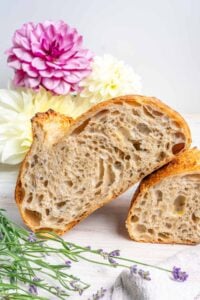 Lavender vanilla sourdough bread sliced in half with flowers in the background.