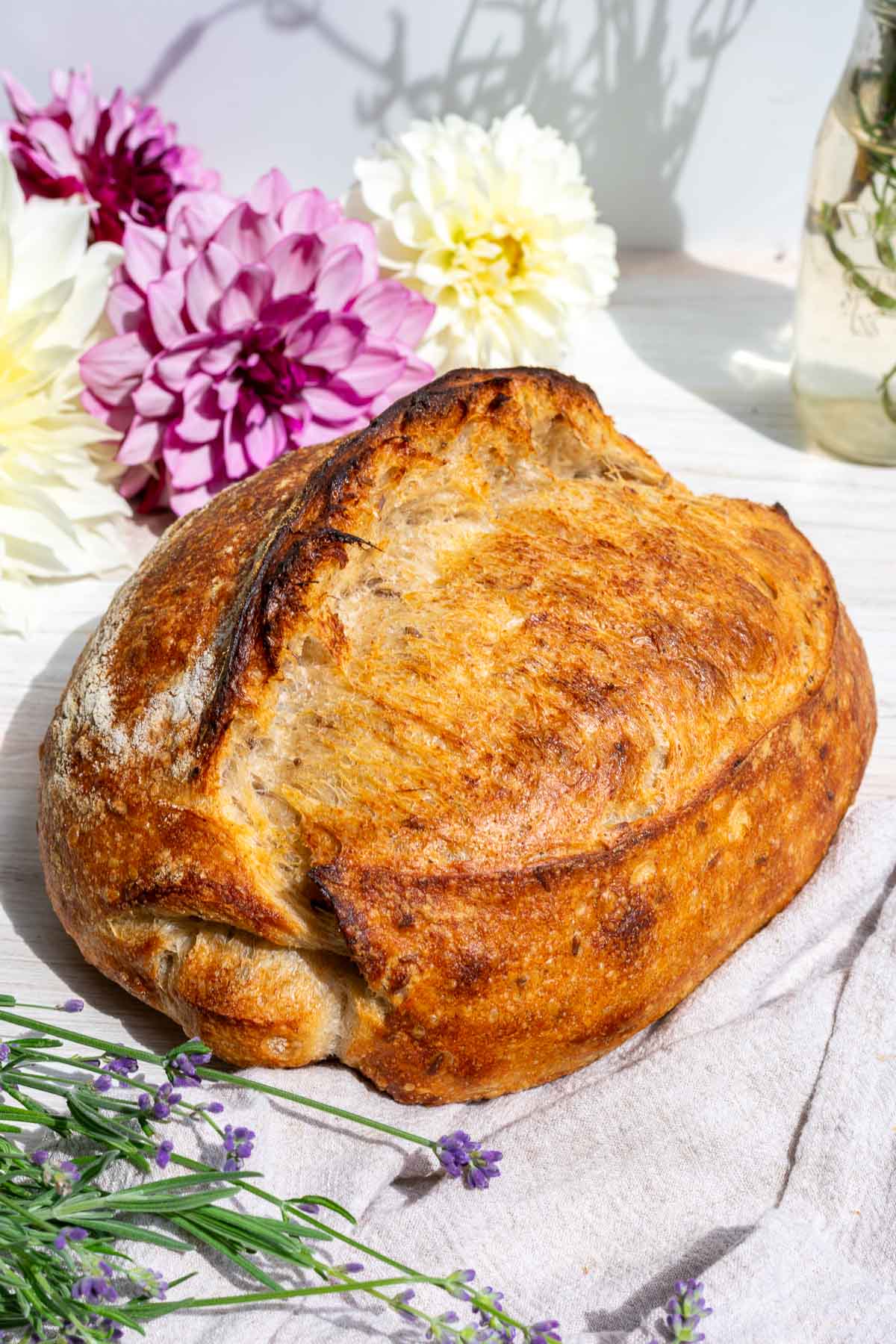 Baked loaf of lavender vanilla sourdough bread with flowers in the background.