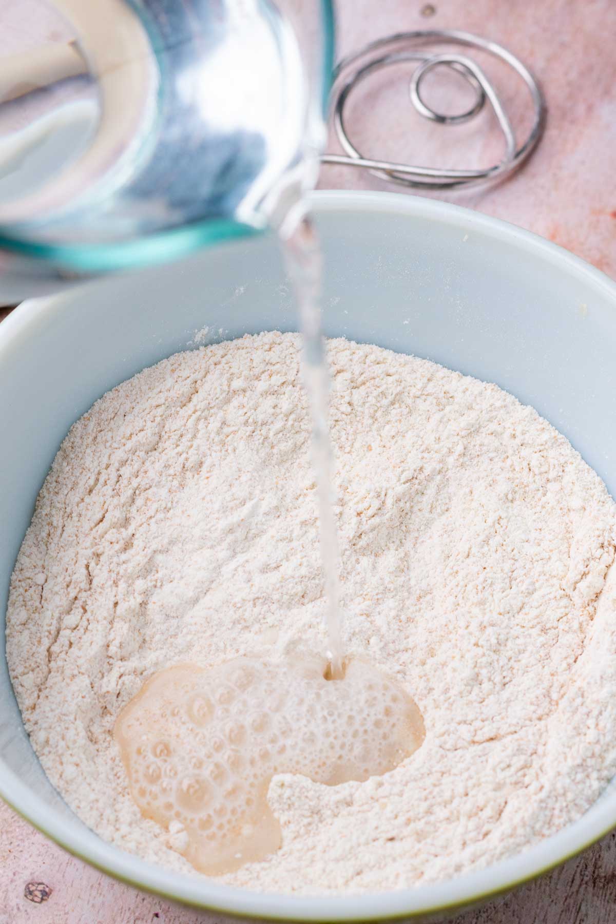 Pouring water into bowl of flour for autolyse.