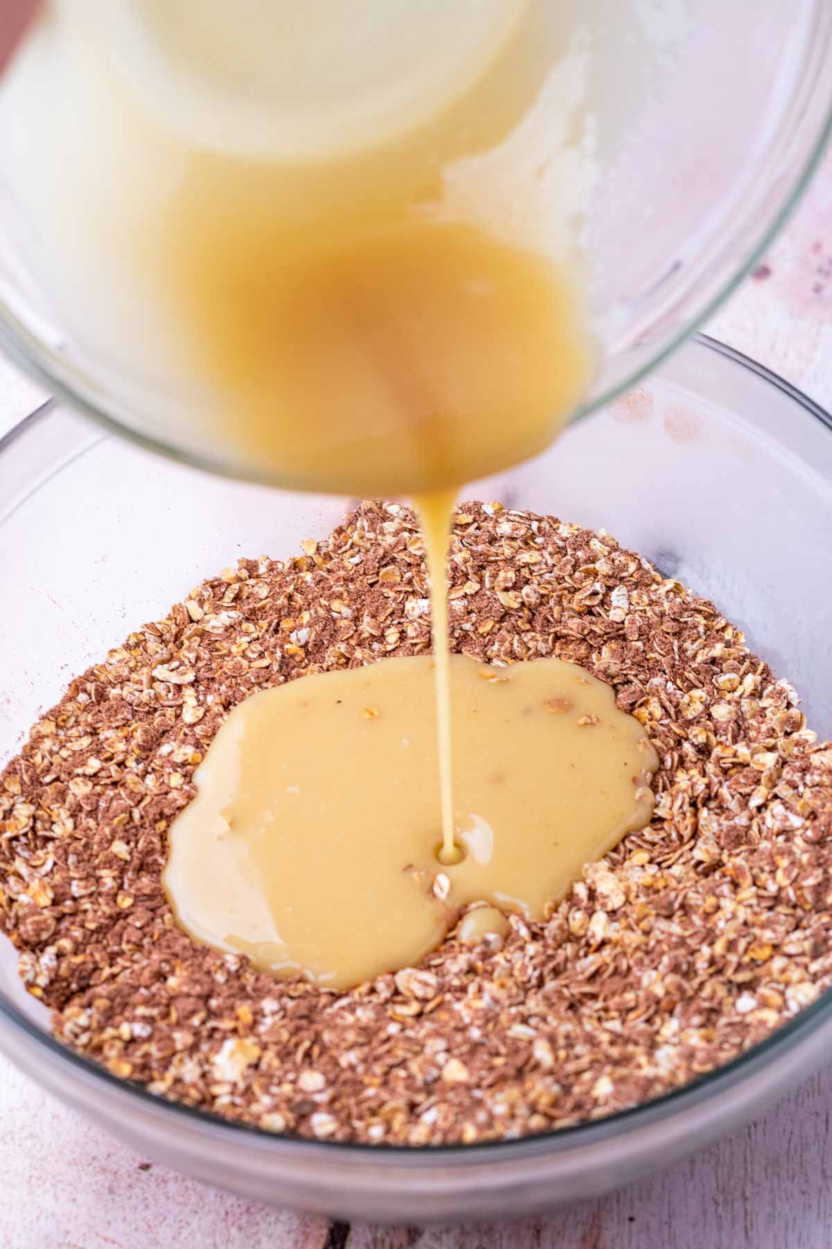 Pouring wet ingredients into bowl of dry ingredients for sourdough granola bars.