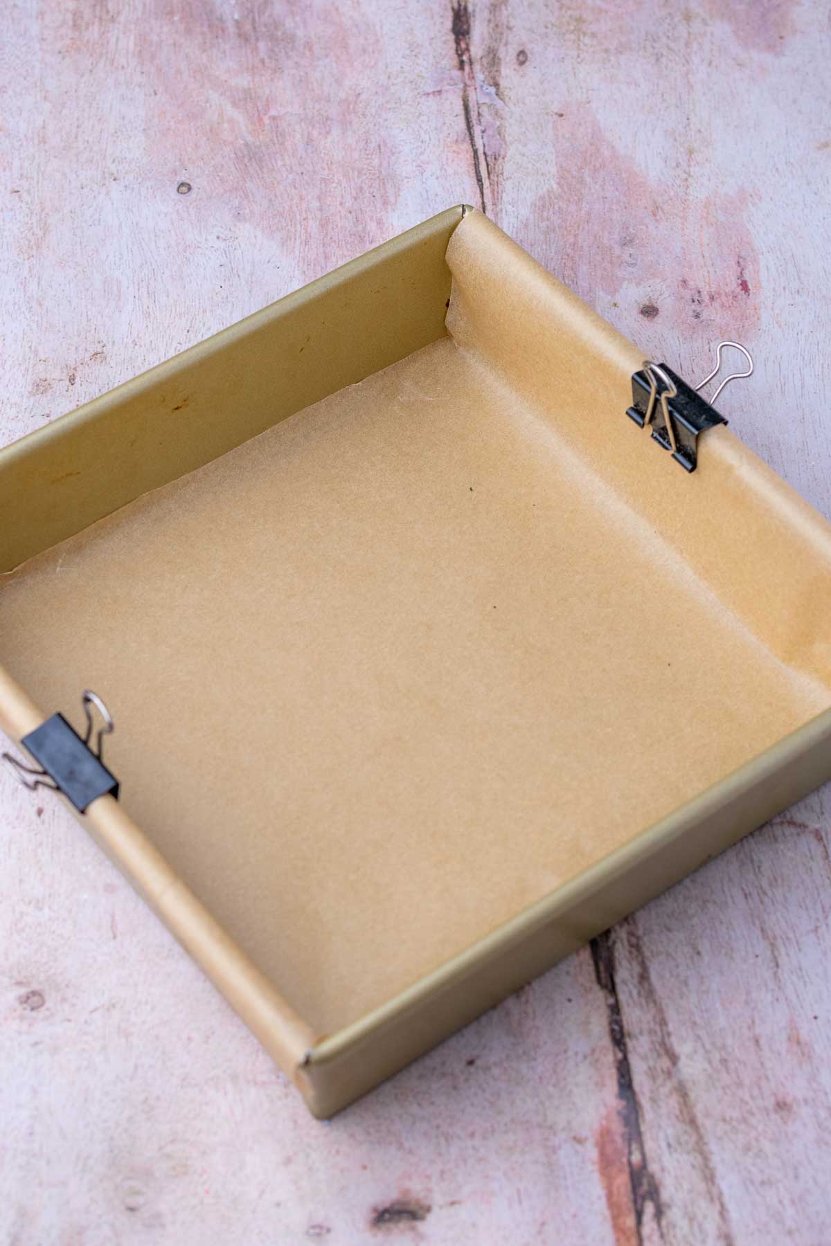 Square baking pan lined with parchment paper.