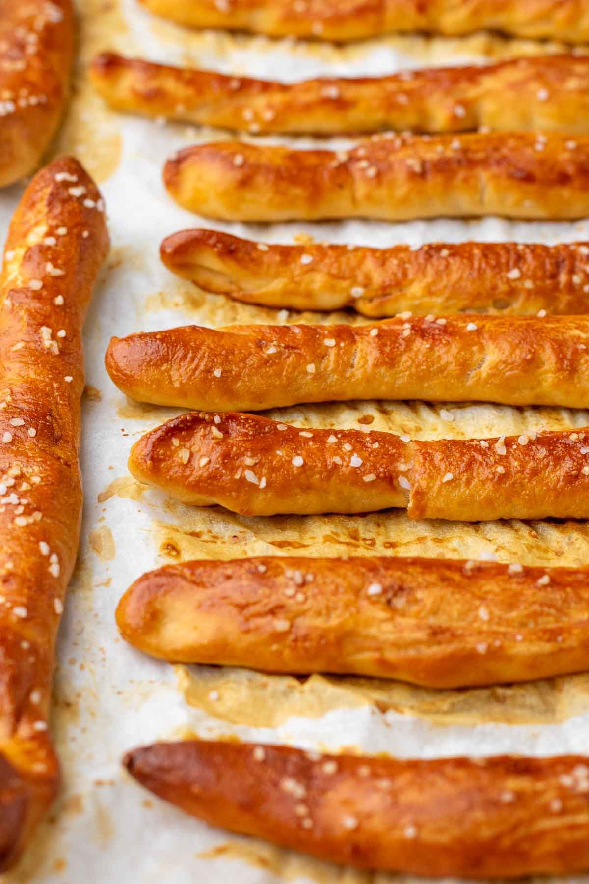 Baked sourdough pretzel rods on a baking sheet.