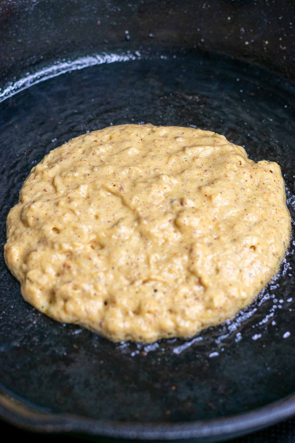 Frying a sourdough pumpkin pancake in cast iron skillet before flipping.