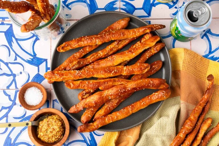 A plate of hard sourdough pretzel rods with mustard and salt.