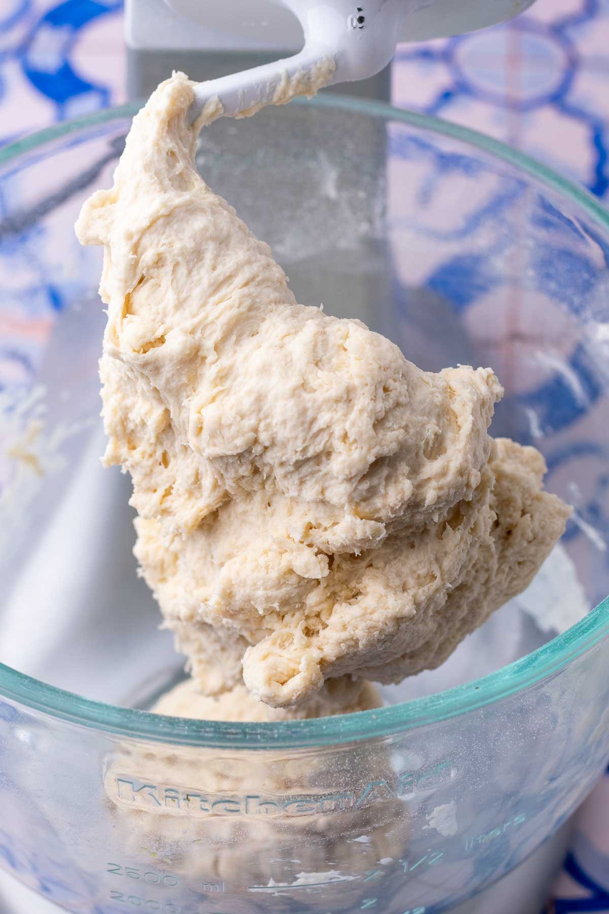 Mixed sourdough pretzel rod dough in a stand mixer bowl with dough hook.