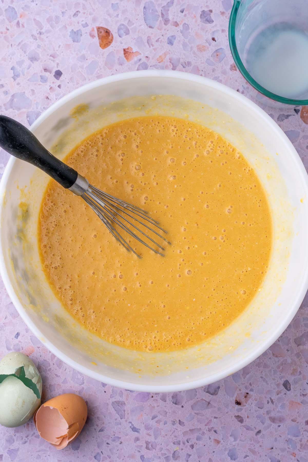 Whisked wet ingredients for sourdough pumpkin pancakes in a bowl with a whisk.