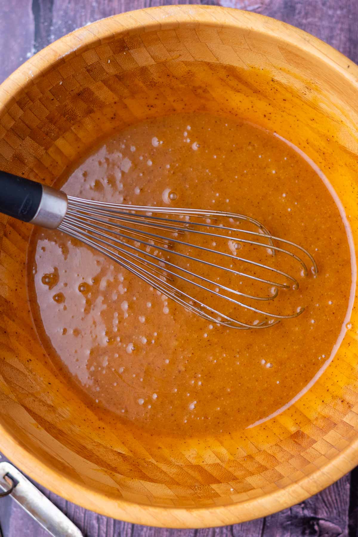 Large bowl with a whisk of wet ingredients for sourdough pumpkin cookies.
