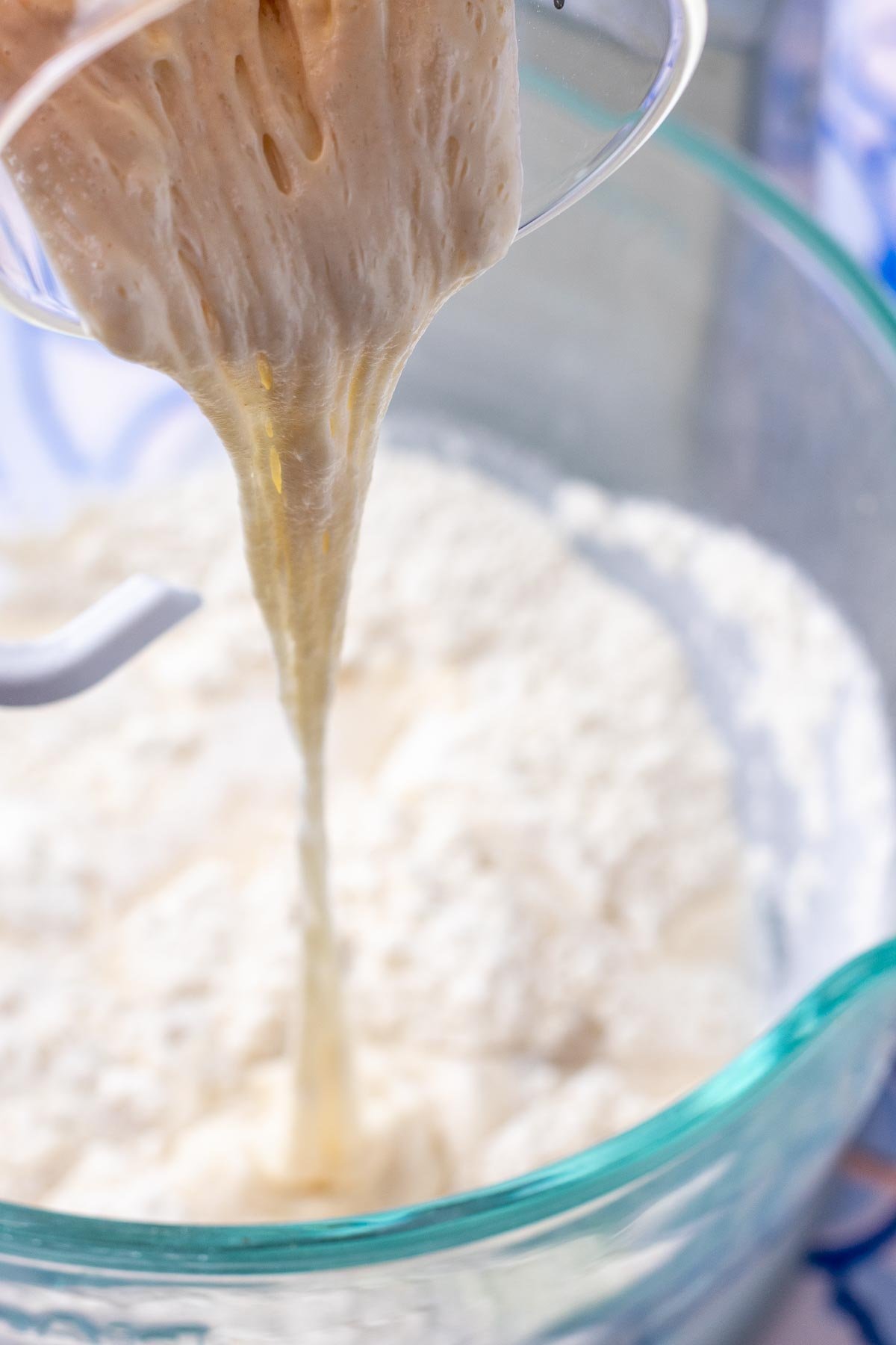 Pouring sourdough starter into bowl with stand mixer.