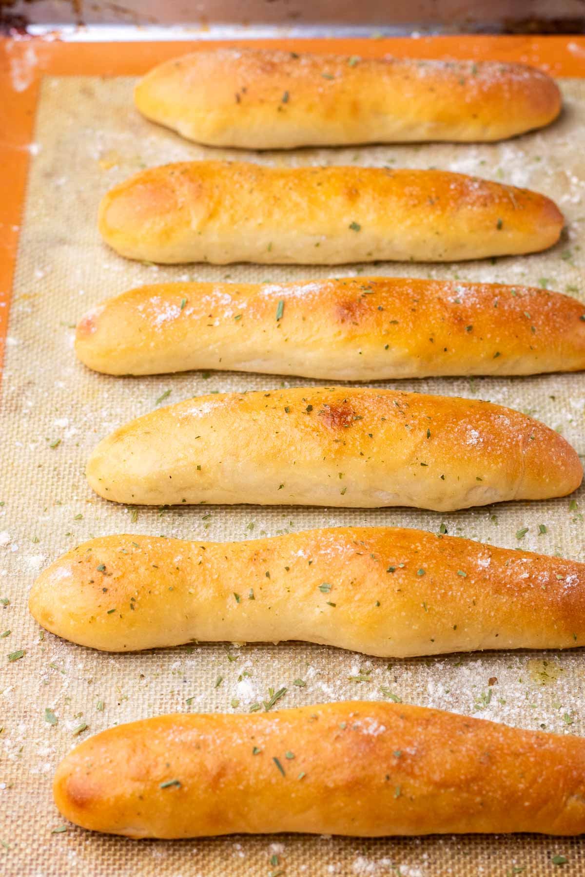Baked sourdough breadsticks on baking sheet.